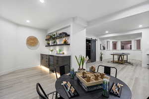 Dining area with a barn door, light wood-type flooring, bar area, and wine cooler