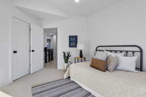 Bedroom featuring light carpet and lofted ceiling