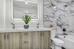 Full bathroom featuring tile walls, vanity, toilet, and shower / bathing tub combination