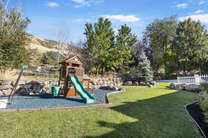 View of playground featuring a lawn and a mountain view