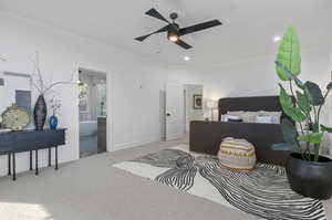 Carpeted bedroom with ornamental molding, ceiling fan, and ensuite bathroom