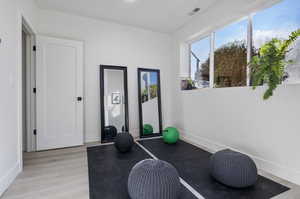 Exercise room with light hardwood / wood-style floors