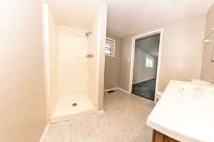 View 2 of the Bathroom featuring a shower, sink, toilet, and tile-patterned flooring