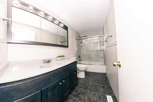 View 1 - Full bathroom with bath / shower combo with glass door, vanity, tile patterned flooring, and toilet newly remodeled 2 years ago.