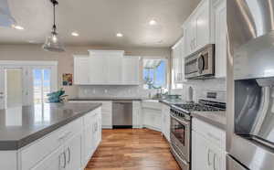 Kitchen with white cabinetry, stainless steel appliances, and a wealth of natural light