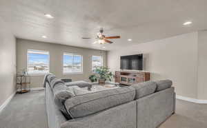 Carpeted living room featuring a textured ceiling and ceiling fan