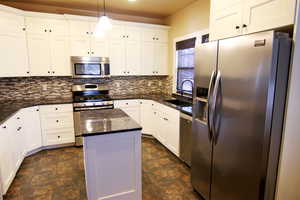 Updated kitchen featuring, white cabinetry, stainless steel appliances, and granite counter tops