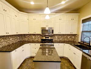 Updated kitchen featuring, white cabinetry, stainless steel appliances, and granite counter tops