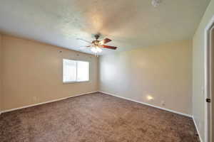 Carpeted spare room with a textured ceiling and ceiling fan