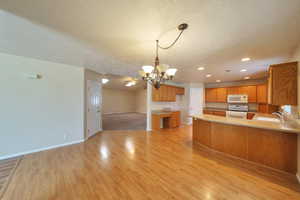 Kitchen featuring sink, a notable chandelier, kitchen peninsula, light hardwood / wood-style flooring, and white appliances