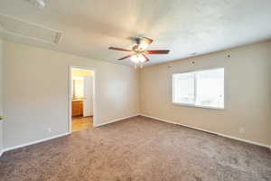 Interior space featuring ensuite bath, ceiling fan, light colored carpet, and a textured ceiling