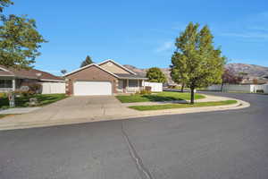 View of front of home with a garage, a mountain view, and a front lawn