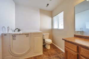 Bathroom with washer / dryer, tile patterned flooring, vanity, and toilet