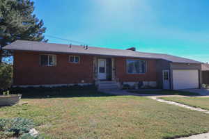 Single story home featuring a front yard and a garage