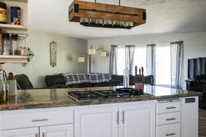 Kitchen with wood-type flooring, white cabinetry, and stainless steel gas cooktop