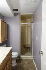 Bathroom with vanity, a textured ceiling, tile patterned floors, walk in shower, and toilet