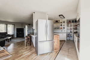 Kitchen featuring light wood-type flooring, stainless steel fridge, and white cabinets