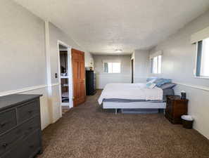 Bedroom with a textured ceiling and dark colored carpet