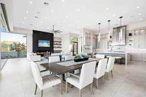 Dining space featuring ceiling fan, a large fireplace, light tile patterned floors, and sink