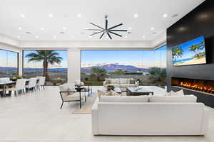 Living room featuring a large fireplace, ceiling fan, and light tile patterned flooring