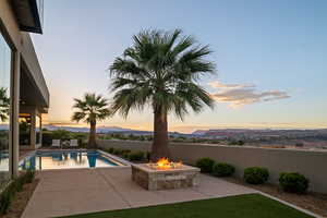 Pool at dusk with a fire pit, a mountain view, and a patio