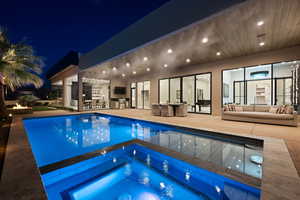 View of swimming pool with outdoor lounge area, an in ground hot tub, a patio area, and exterior kitchen