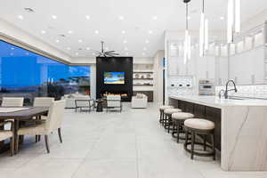 Interior space with oven, sink, decorative light fixtures, light stone counters, and white cabinetry