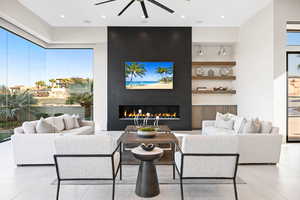 Living room with light tile patterned floors, a large fireplace, and ceiling fan