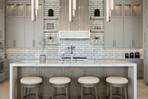 Kitchen with tasteful backsplash, light stone counters, stainless steel oven, white oven, and a breakfast bar area