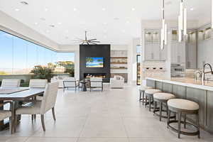 Tiled dining room featuring ceiling fan, sink, and a fireplace