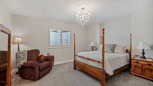 Carpeted bedroom featuring a textured ceiling and a chandelier