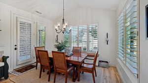 Dining space featuring a notable chandelier, lofted ceiling, and light hardwood / wood-style floors