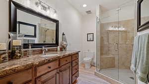 Bathroom with vanity, walk in shower, hardwood / wood-style floors, and toilet