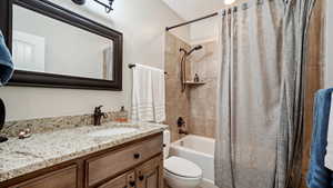 Full bathroom featuring vanity, shower / tub combo, toilet, and a textured ceiling