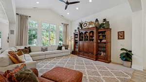 Living room with light hardwood / wood-style floors, lofted ceiling, and ceiling fan