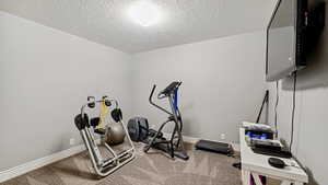 Exercise room with a textured ceiling and carpet floors