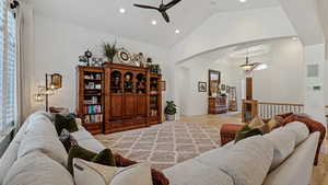 Living room with high vaulted ceiling, light wood-type flooring, and ceiling fan