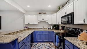 Kitchen with blue cabinets, white cabinetry, and black appliances