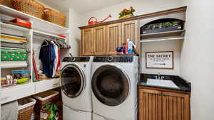 Laundry room with a textured ceiling, washing machine and dryer, sink, and cabinets