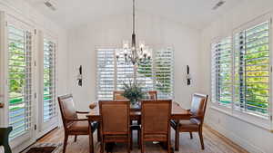 Dining room featuring light wood-type flooring, vaulted ceiling, and plenty of natural light