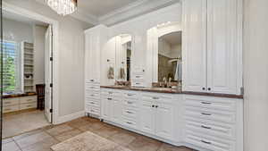 Master Bathroom with vanity, ornamental molding, a shower with shower door, a chandelier, and tile patterned floors