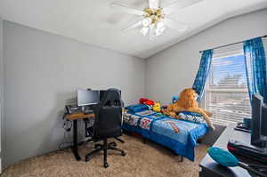 Carpeted bedroom with vaulted ceiling and ceiling fan