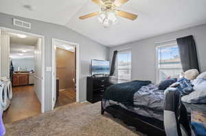 Bedroom featuring washing machine and dryer, lofted ceiling, dark carpet, ceiling fan, and sink