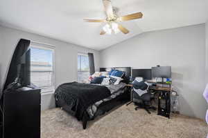 Carpeted bedroom with lofted ceiling and ceiling fan