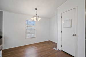 Empty room with ornamental molding, a chandelier, a textured ceiling, and dark hardwood / wood-style flooring