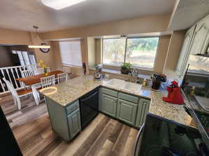 Kitchen featuring black dishwasher, hardwood / wood-style floors, sink, and kitchen peninsula