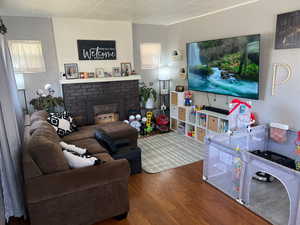 Living room with a brick fireplace and wood-type flooring