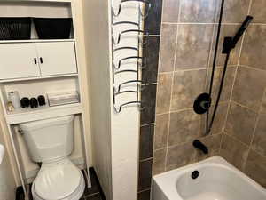 Bathroom featuring tiled shower / bath and toilet