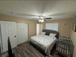 Bedroom featuring a textured ceiling, dark wood-type flooring, ceiling fan, and a closet