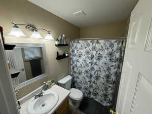 Master Bathroom with a textured ceiling, curtained shower, vanity, and toilet